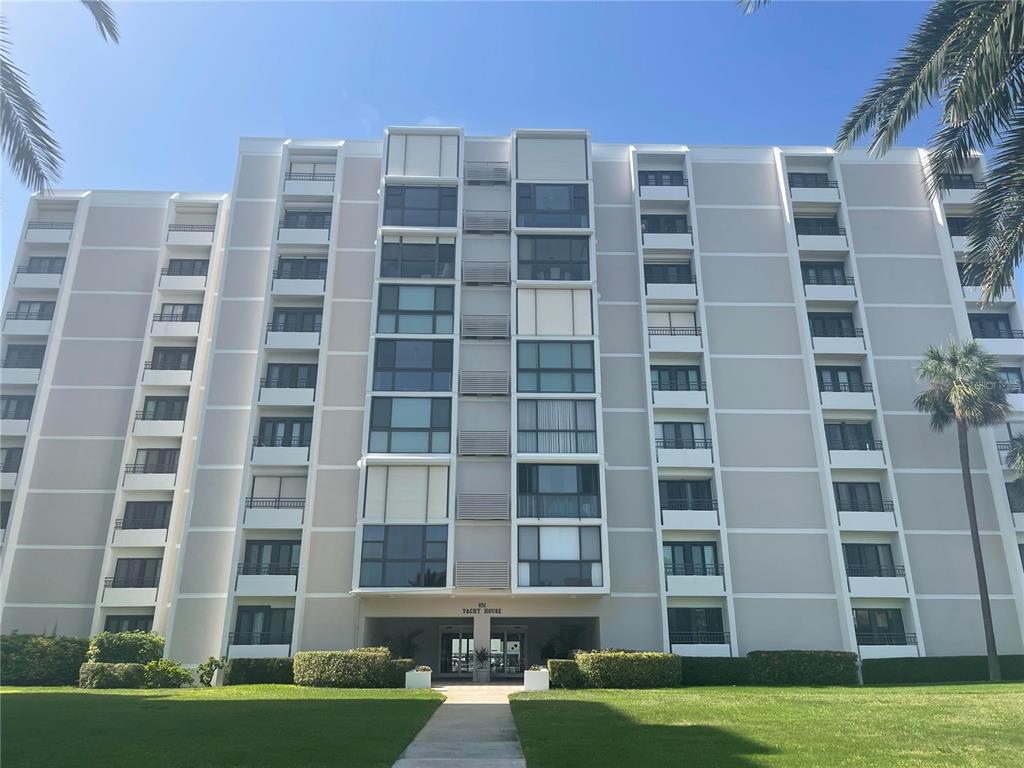 A multi-story residential building with a central entrance and palm trees on a sunny day — 851 BAYWAY BOULEVARD UNIT 103, CLEARWATER BEACH, FL