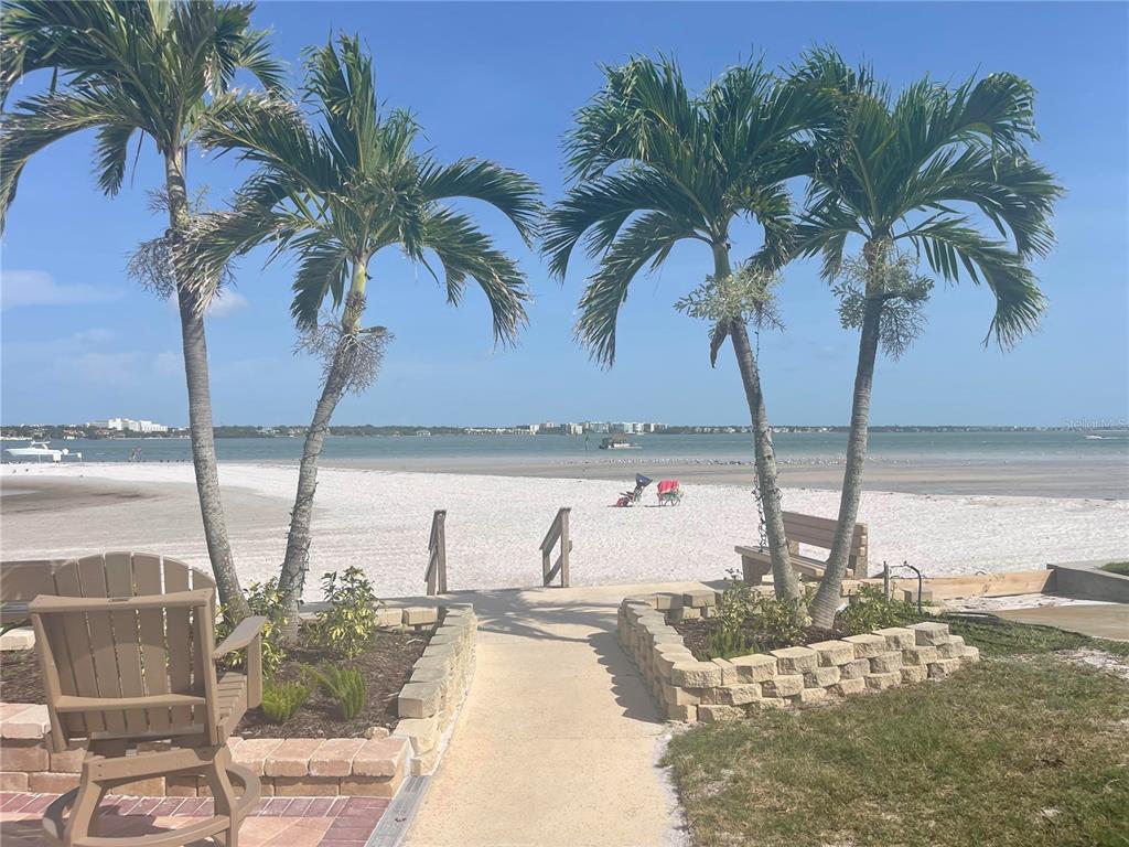 A paved path leads through palm trees to a white sand beach and the ocean — 851 BAYWAY BOULEVARD UNIT 103, CLEARWATER BEACH, FL
