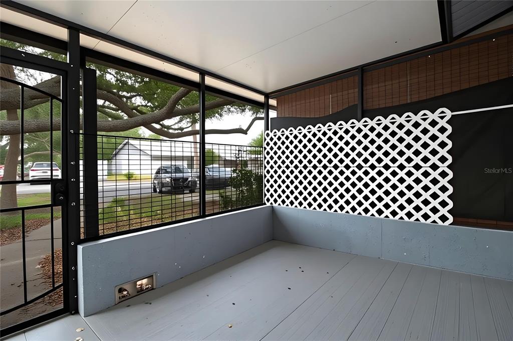 A screened-in porch features a gray floor, a low concrete wall, and white lattice privacy screening — 7115 PARKSIDE VILLAS DR N, ST PETERSBURG, FL