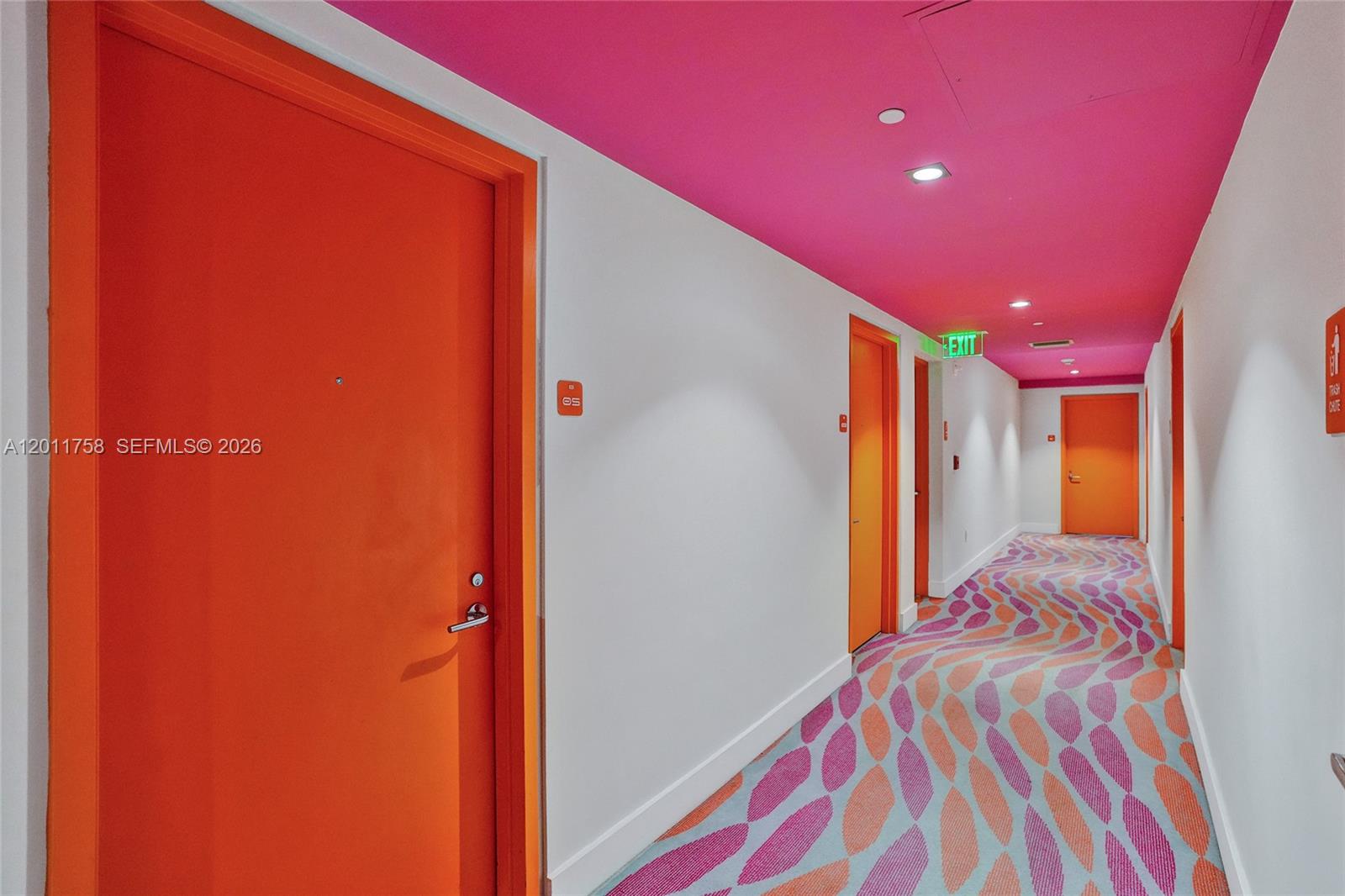 A hallway features bright orange doors, a vibrant pink ceiling, and patterned carpet flooring — 31 SE 6th St # 805, Miami FL 33131, MIAMI, FL