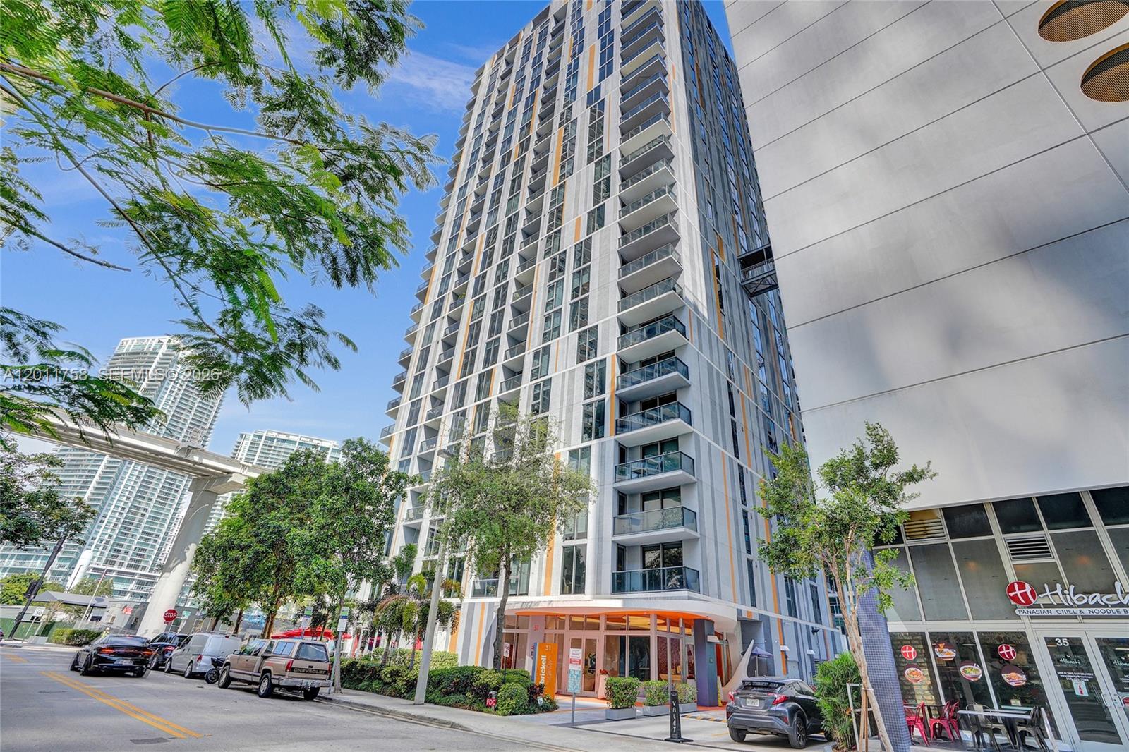 A low-angle exterior view of a modern high-rise apartment building with a ground-floor restaurant — 31 SE 6th St # 805, Miami FL 33131, MIAMI, FL