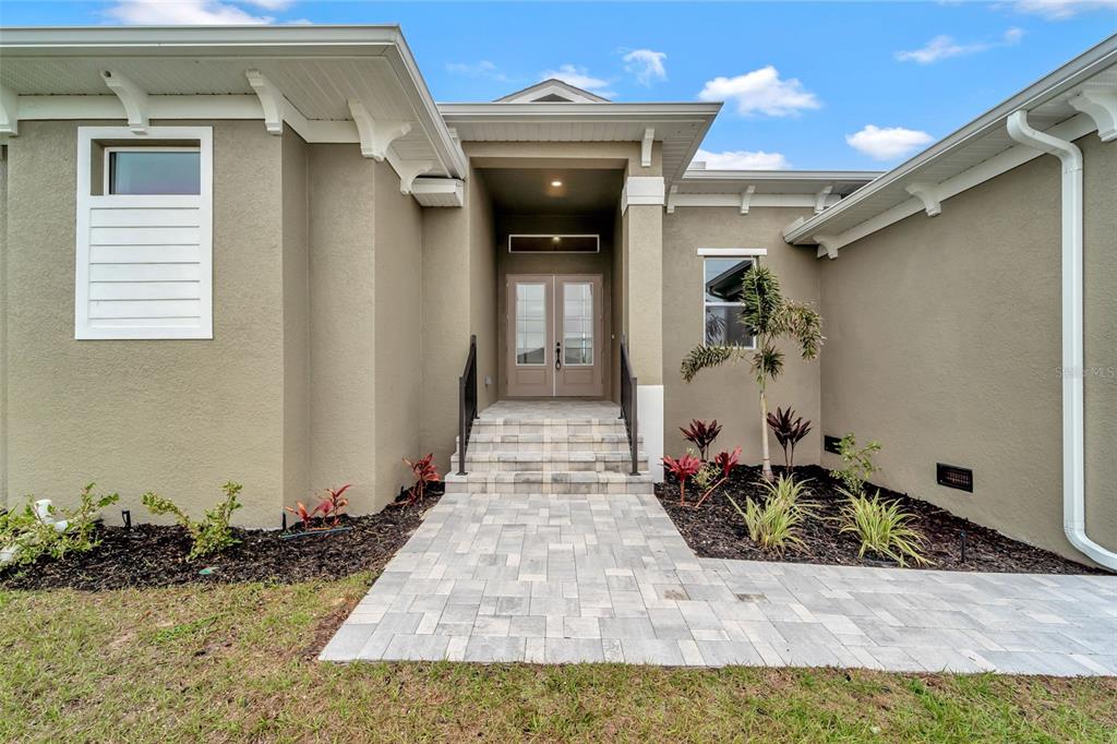 The exterior of a house features a stone walkway leading to double front doors — 10508 MCALESTER CIRCLE, PORT CHARLOTTE, FL