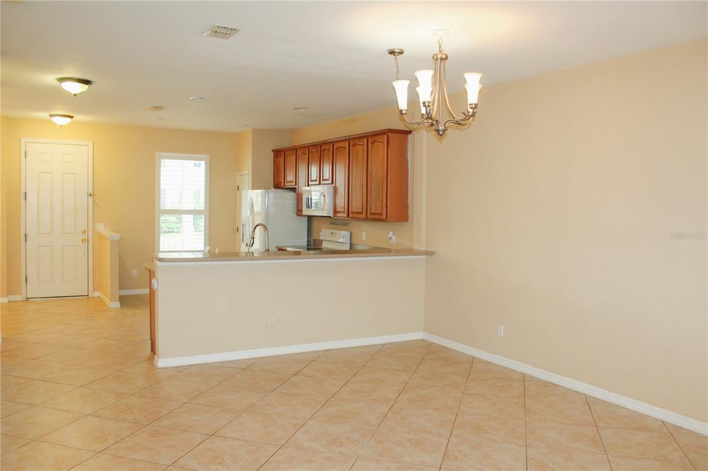 An open-concept kitchen with wood cabinets and a breakfast bar overlooks a tiled dining area — 14252 CONFETTI DRIVE, WINDERMERE, FL