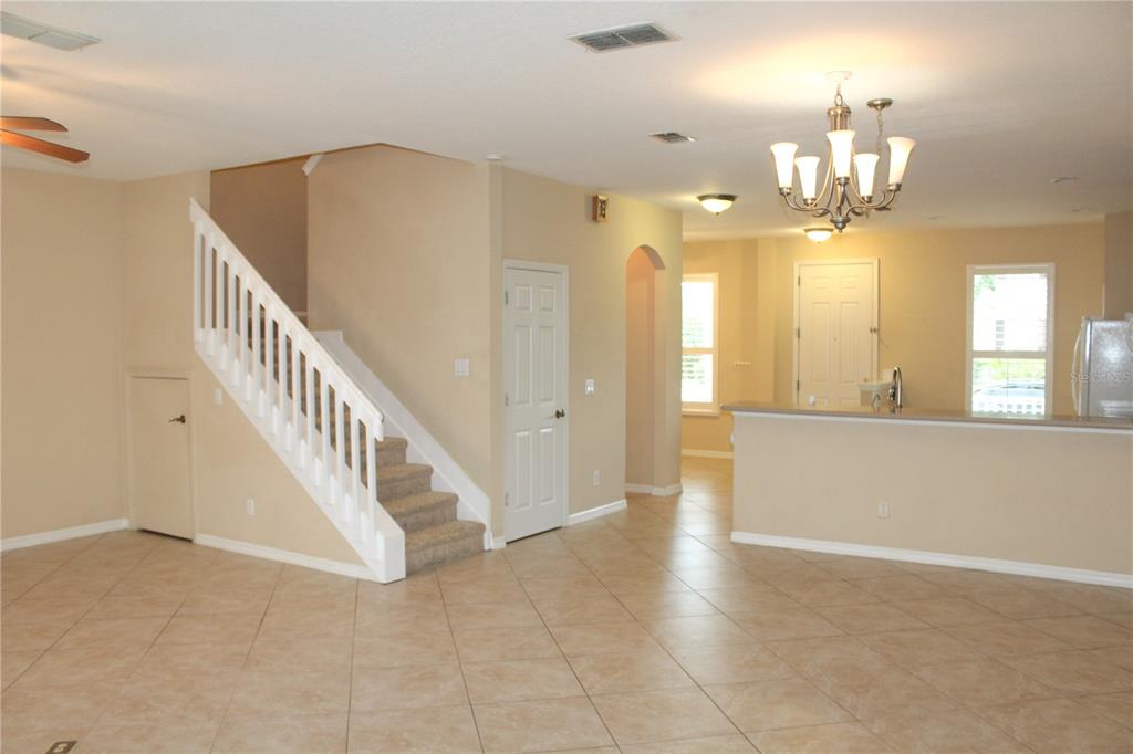 An open-concept living area features tile flooring, a staircase with white railings, and a chandelier — 14252 CONFETTI DRIVE, WINDERMERE, FL