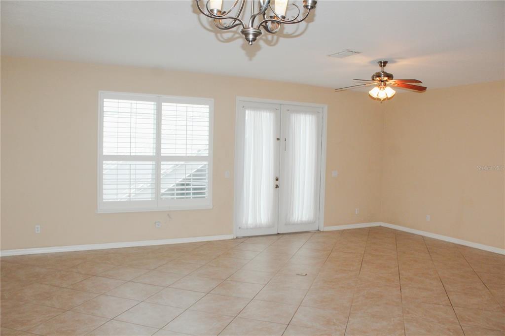 A spacious room features beige walls, tiled floors, a ceiling fan, and French doors — 14252 CONFETTI DRIVE, WINDERMERE, FL