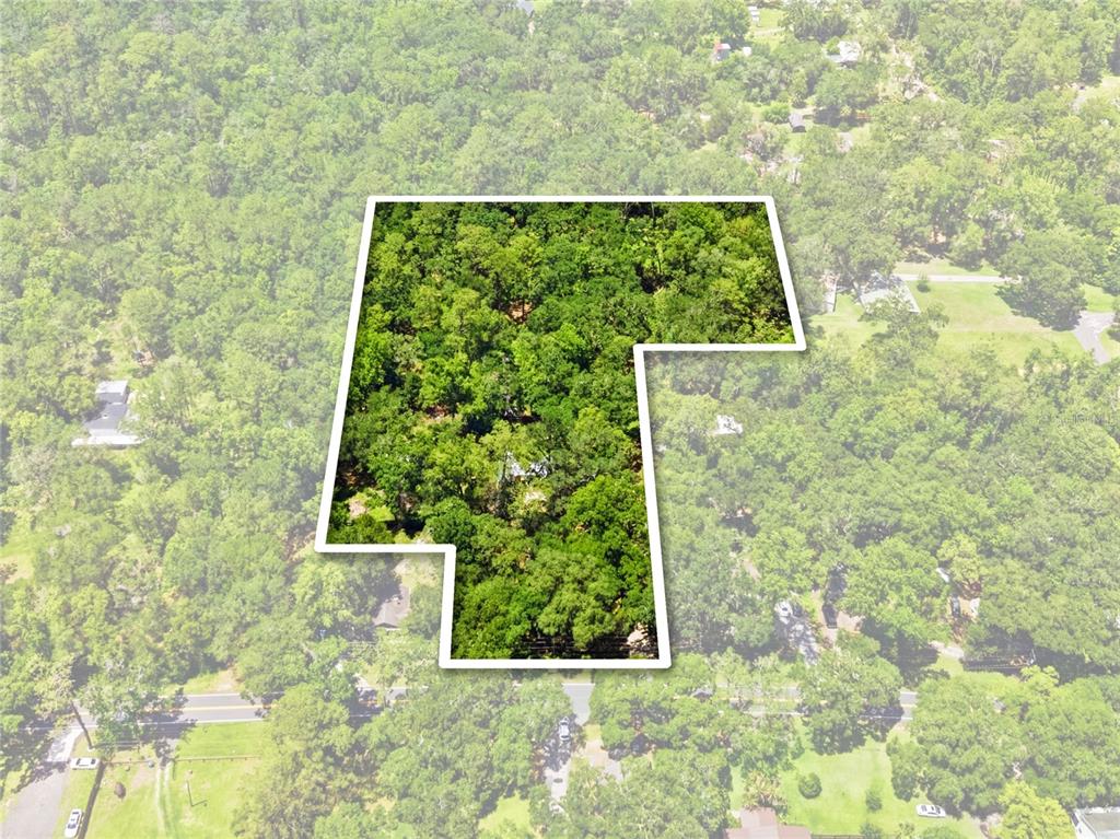 An aerial view shows a wooded lot outlined in white against a surrounding forest — 19199 FORT DADE AVENUE, BROOKSVILLE, FL