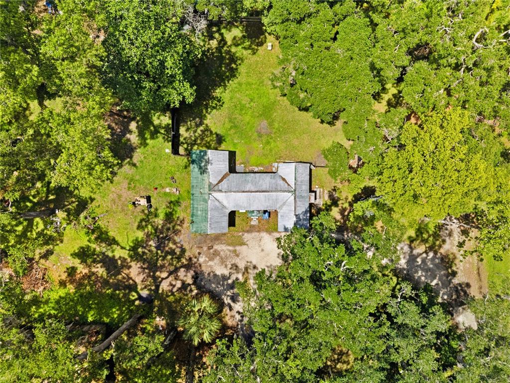 An aerial view shows a house with a U-shaped roof surrounded by trees and grass — 19199 FORT DADE AVENUE, BROOKSVILLE, FL