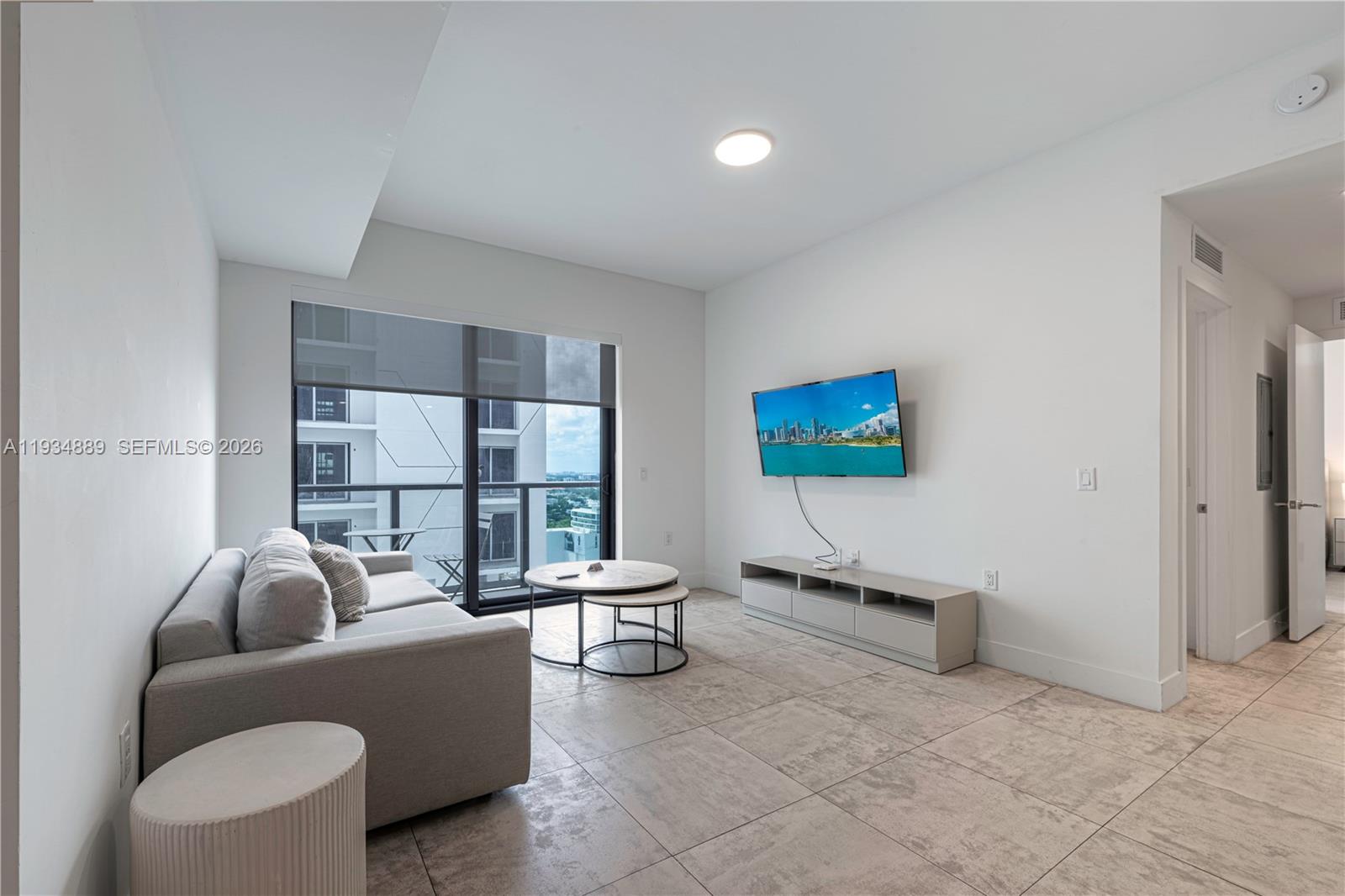 A modern living room features a grey sofa, a wall-mounted television, and tile flooring — 239 SW 9th St # 2103, Miami FL 33130, MIAMI, FL