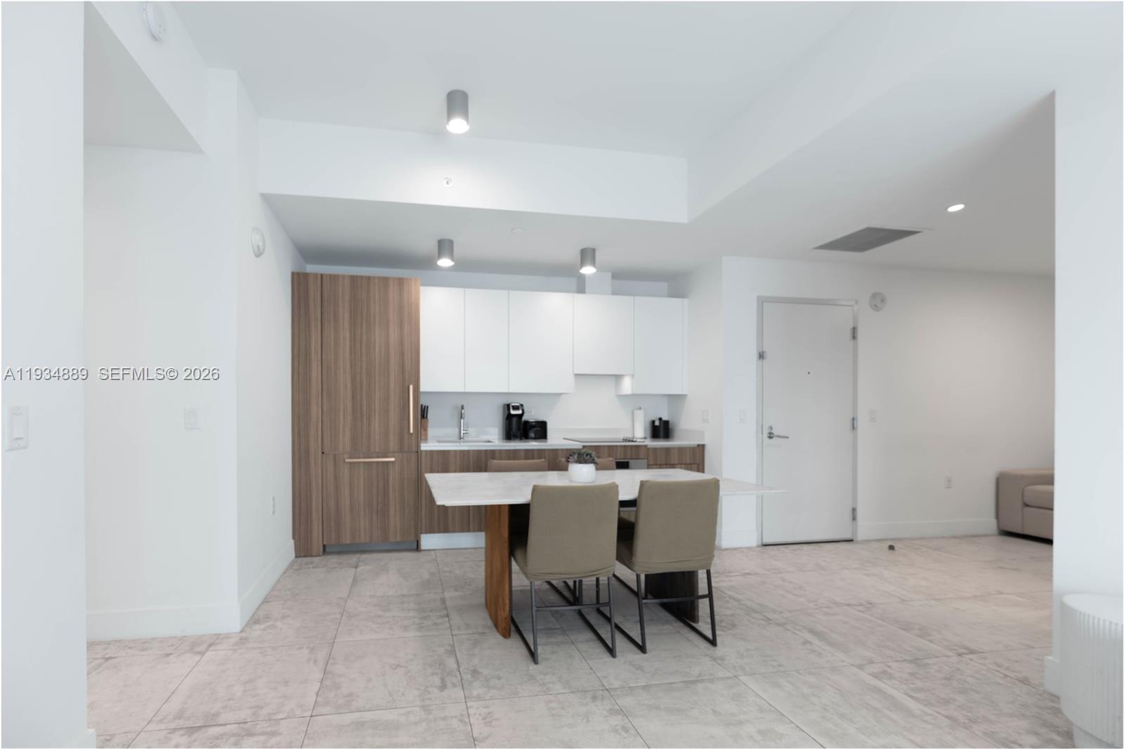 A modern kitchen features white upper cabinets, wood-paneled appliances, and a central dining table — 239 SW 9th St # 2103, Miami FL 33130, MIAMI, FL