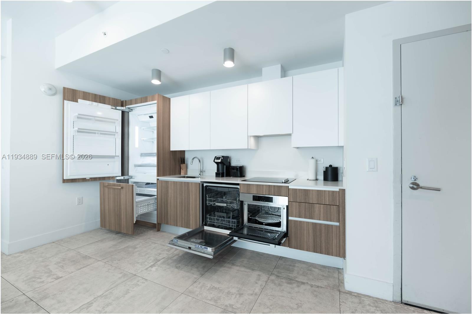 A modern kitchen features white upper cabinets, wood-grain lower cabinets, and stainless steel appliances — 239 SW 9th St # 2103, Miami FL 33130, MIAMI, FL