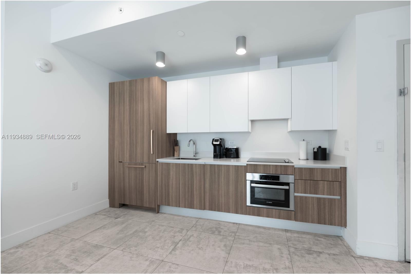A modern kitchen features wood-grain cabinetry, white upper cabinets, stainless steel appliances, and tile flooring — 239 SW 9th St # 2103, Miami FL 33130, MIAMI, FL