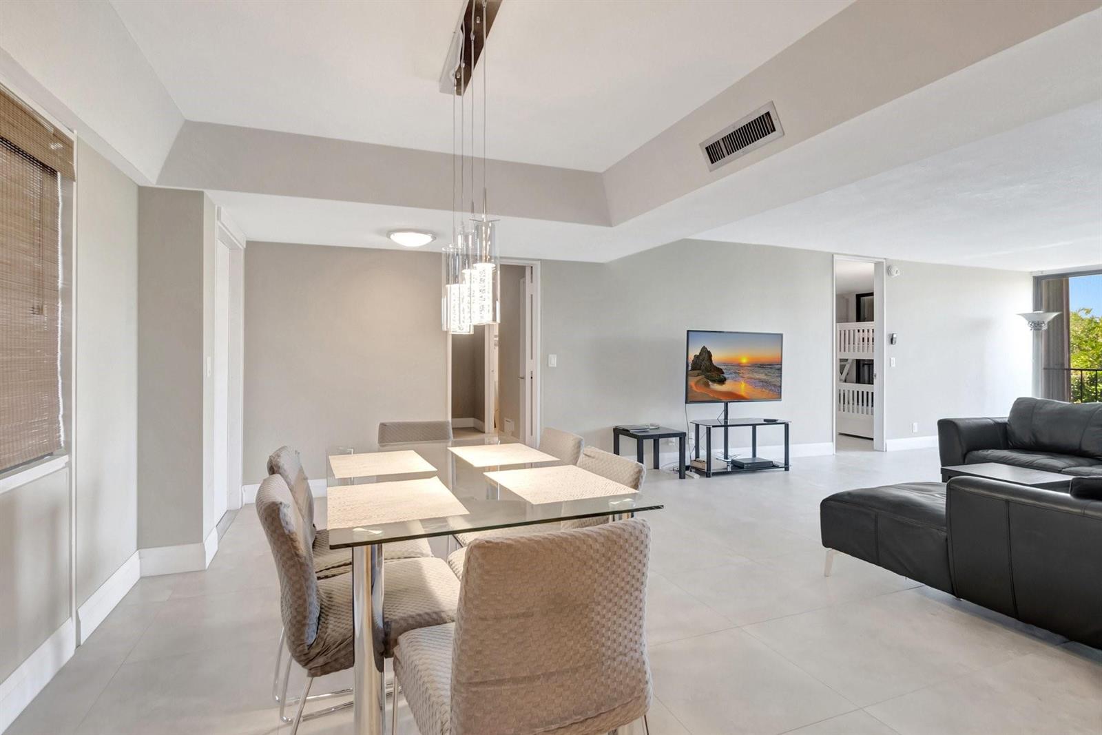 A dining area with a glass table and chairs sits adjacent to a living room — 501 SW 11th Place # 403, Boca Raton FL 33432, BOCA RATON, FL