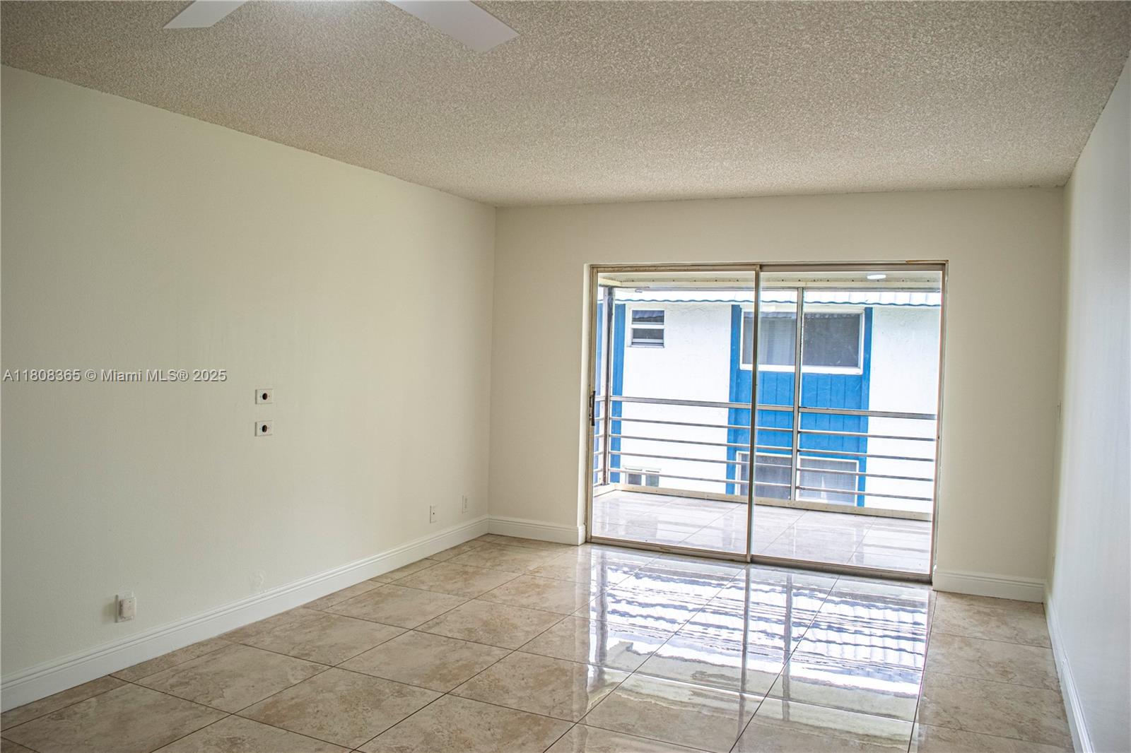 An empty room features beige tile flooring, white walls, and a sliding glass balcony door — 3090 Holiday Springs Blvd # 305, Margate FL 33063, MARGATE, FL