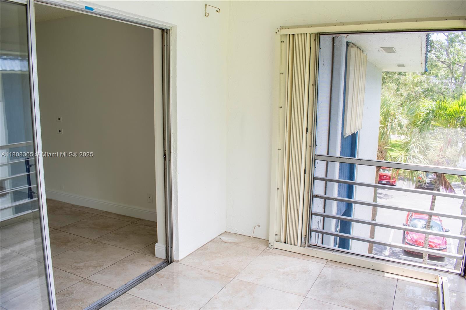 A tiled balcony features a sliding glass door entrance and a metal railing overlooking parking — 3090 Holiday Springs Blvd # 305, Margate FL 33063, MARGATE, FL
