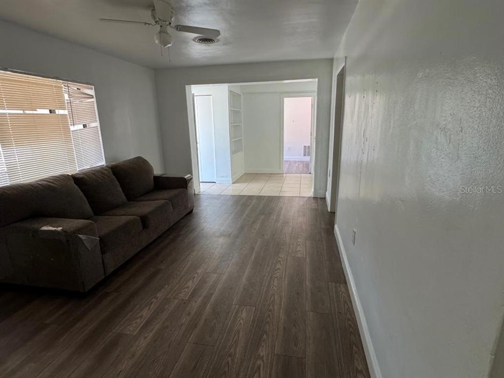 A living room features wood-look flooring, a brown sofa, and an opening to a tiled area — 1412 N GARFIELD AVENUE, DELAND, FL