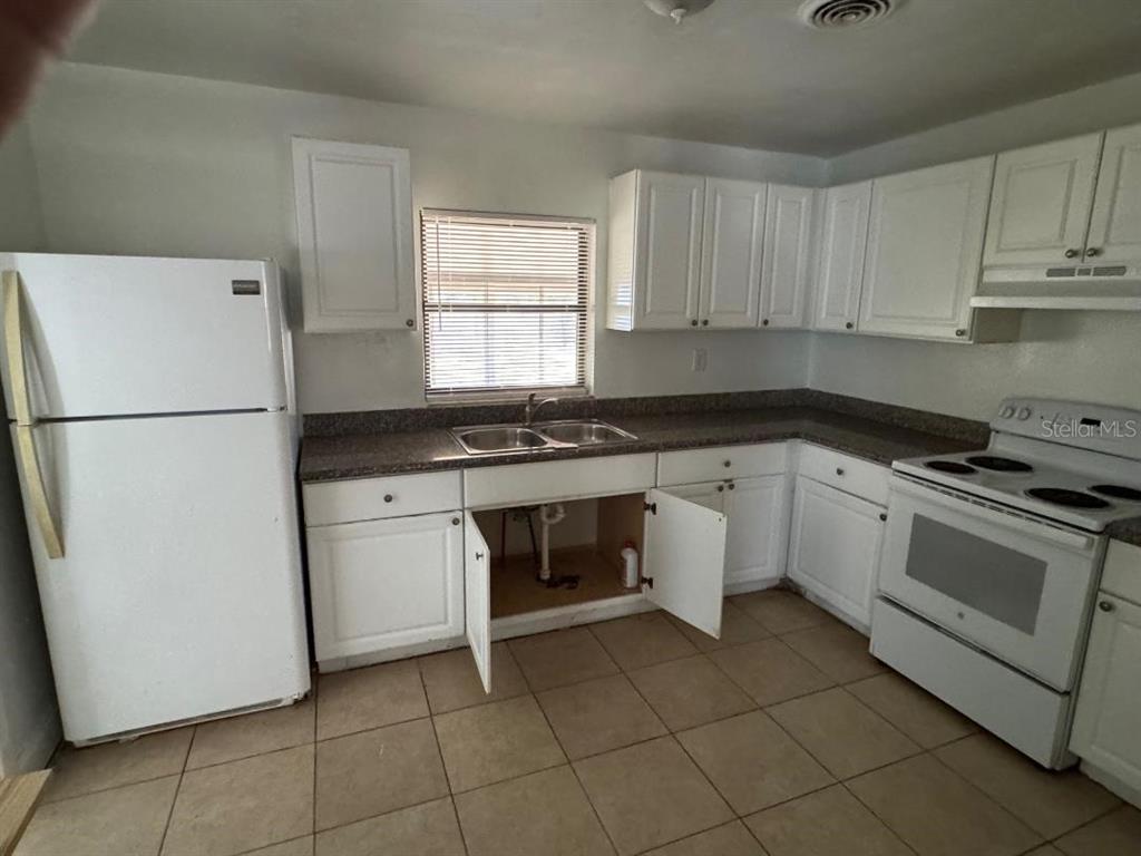 A kitchen with white cabinets, white appliances, a double sink, and tiled flooring — 1412 N GARFIELD AVENUE, DELAND, FL