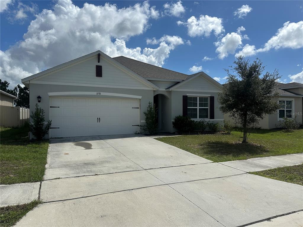 A single-story suburban house with a two-car garage and a concrete driveway — 1292 SUGARWOOD STREET, DAVENPORT, FL