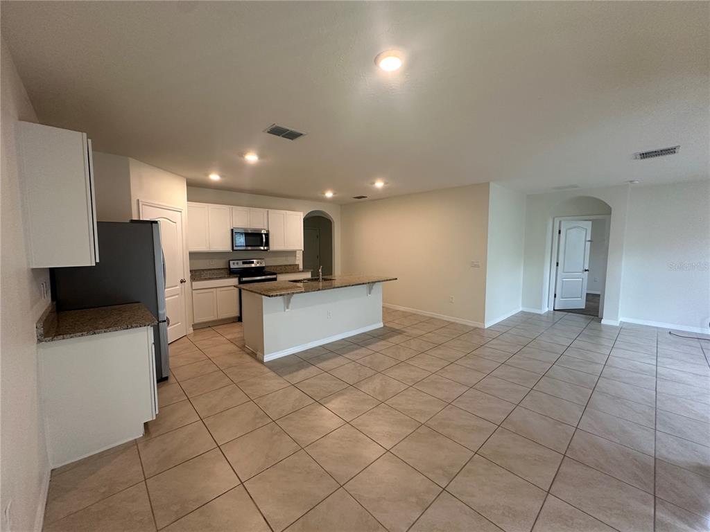 A kitchen with white cabinets, granite countertops, a center island, and tile flooring — 1292 SUGARWOOD STREET, DAVENPORT, FL