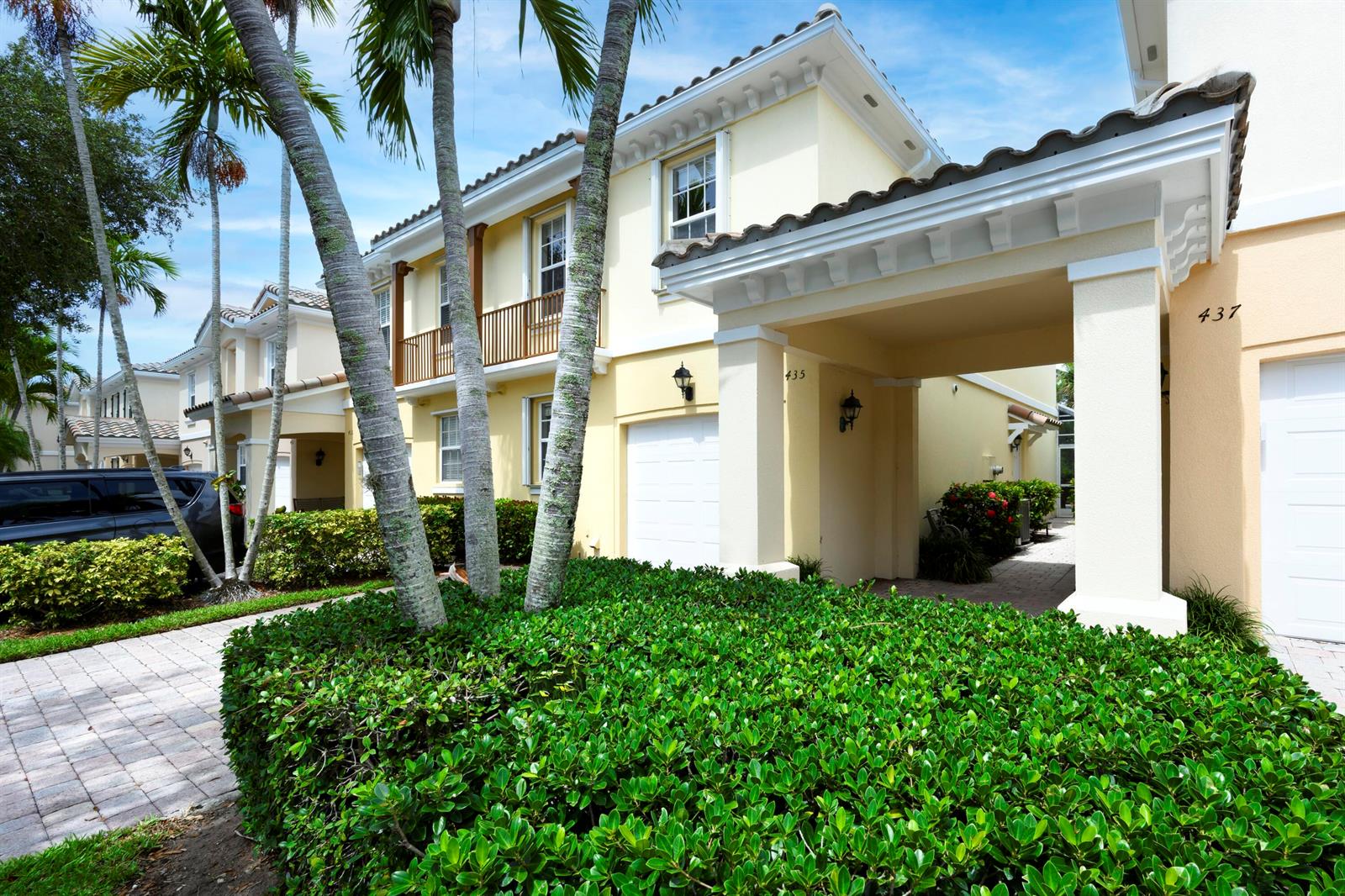 A two-story yellow townhouse with a covered entryway and palm trees in the front yard — 435 Capistrano Drive, Palm Beach Gardens FL 33410, PALM BEACH GARDENS, FL