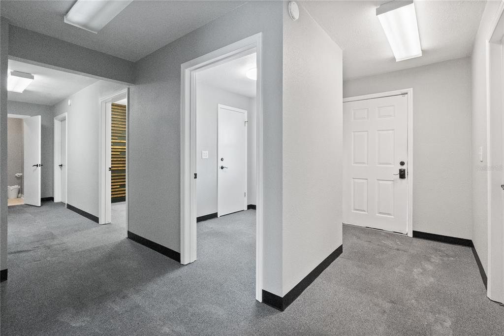 A hallway with gray carpet, white walls, and multiple doorways leading to other rooms — 684 W MONTROSE STREET UNIT 690/E, CLERMONT, FL