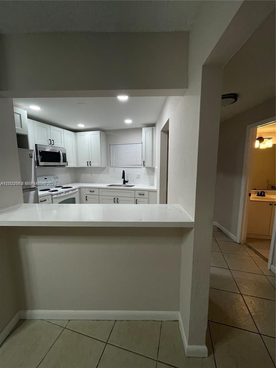 A kitchen features white cabinets, stainless steel appliances, and a breakfast bar counter — 4255 N University Dr # 109, Sunrise FL 33351, SUNRISE, FL