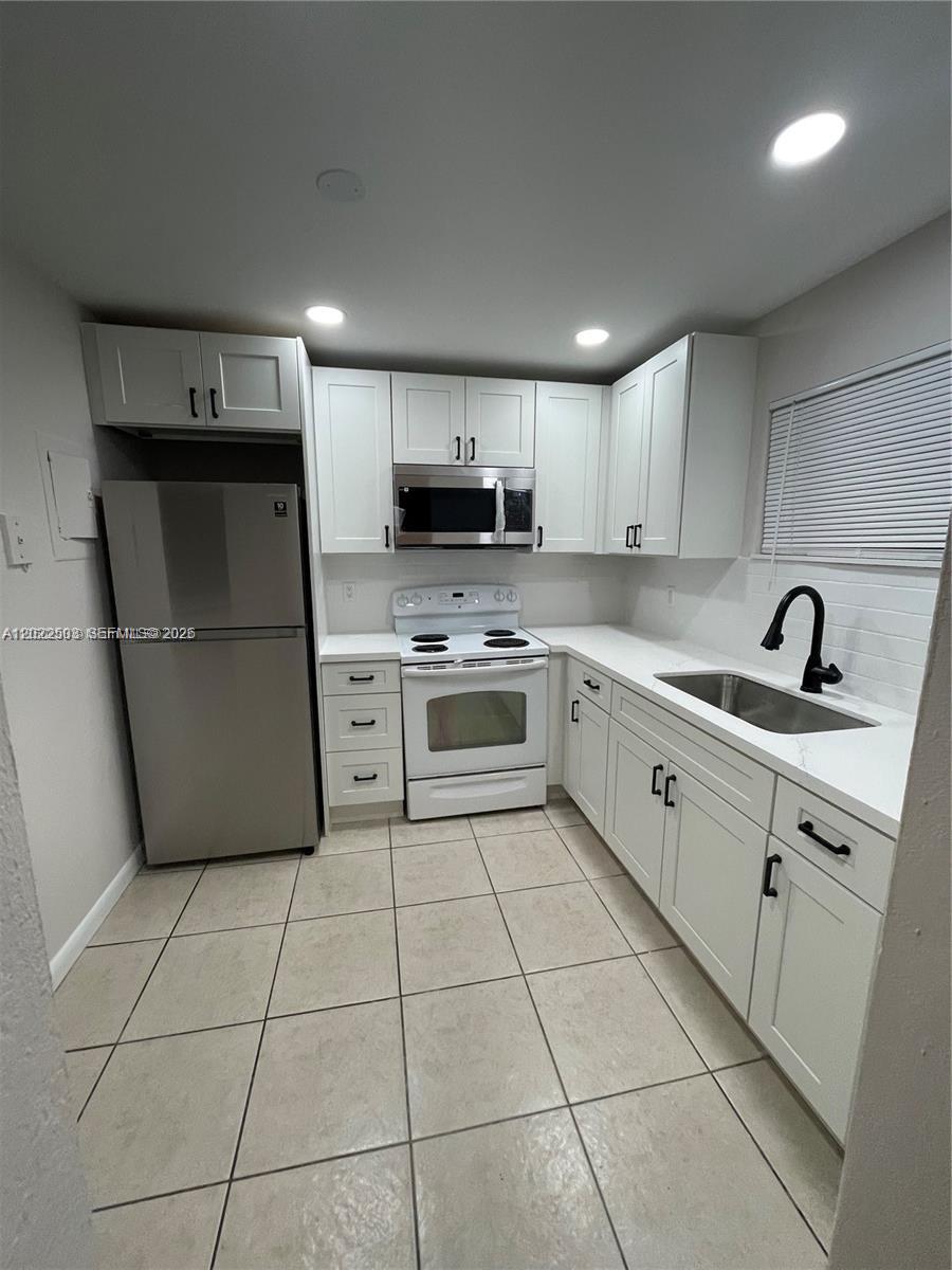 A kitchen features white cabinets, stainless steel appliances, a white countertop, and tiled flooring — 4255 N University Dr # 109, Sunrise FL 33351, SUNRISE, FL