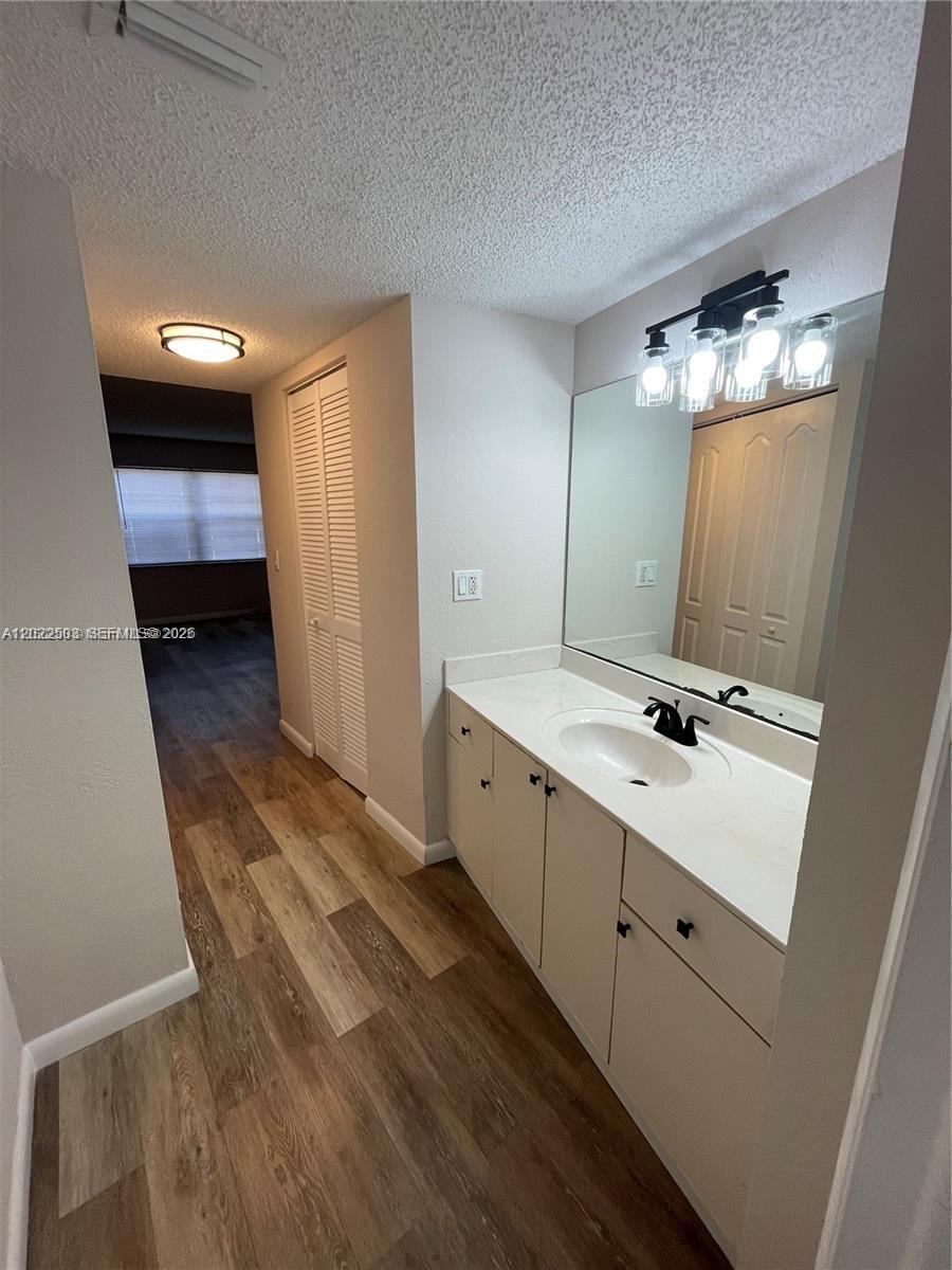 A bathroom vanity with a white countertop and black faucet sits beside a hallway — 4255 N University Dr # 109, Sunrise FL 33351, SUNRISE, FL