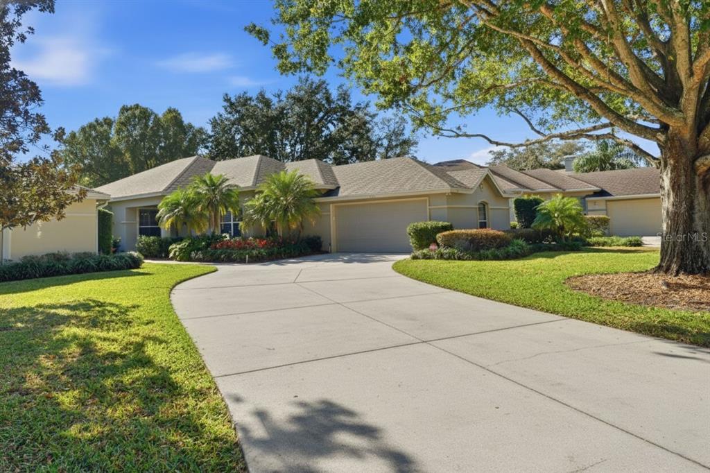 A single-story house with a concrete driveway, a two-car garage, and mature landscaping — 106 JARDIN LANE, WINTER HAVEN, FL