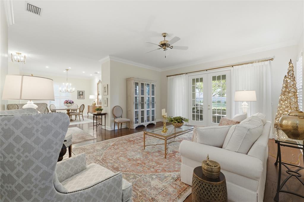 A bright living room features a white sofa, patterned armchairs, and French doors — 106 JARDIN LANE, WINTER HAVEN, FL