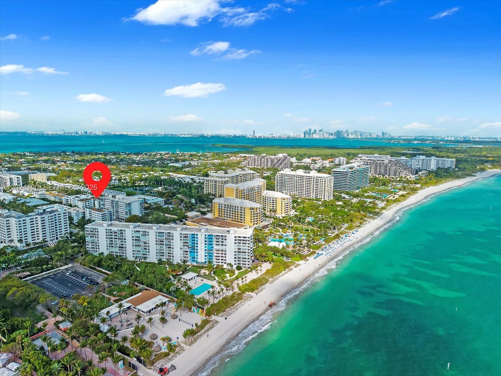 An aerial view shows beachfront apartment buildings along a coastline with a red location pin — 300 Galen Dr # 306, Key Biscayne FL 33149, KEY BISCAYNE, FL