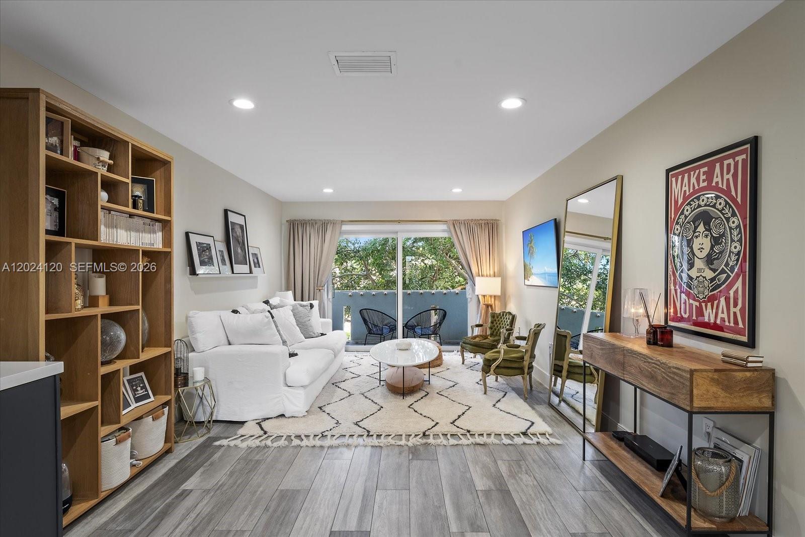 A living room features a white sofa, patterned rug, wood shelving, and a balcony view — 300 Galen Dr # 306, Key Biscayne FL 33149, KEY BISCAYNE, FL