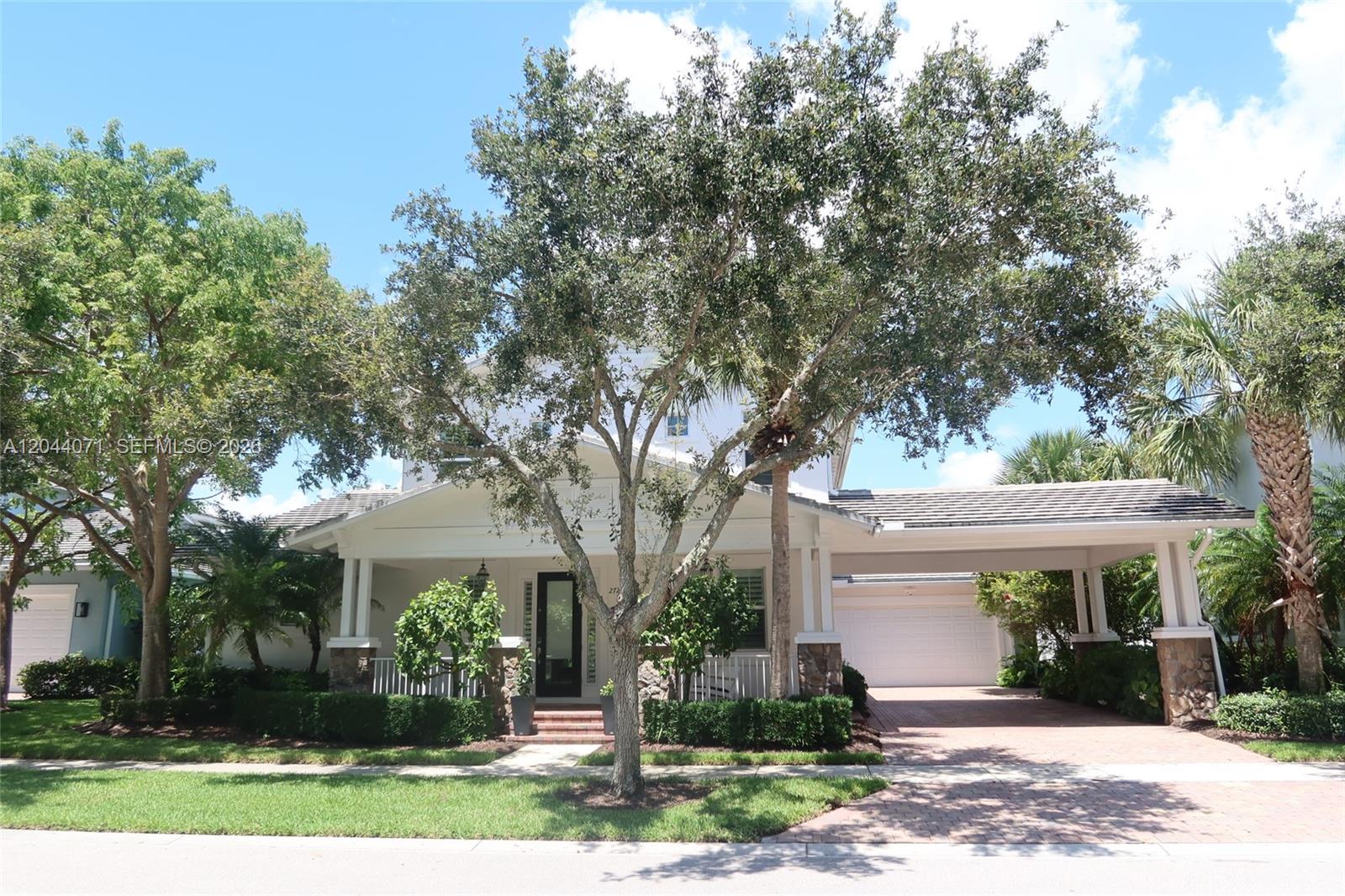 A two-story white house features a front porch, a paved driveway, and a large tree — 2724 Wymberly Dr, Jupiter FL 33458, JUPITER, FL