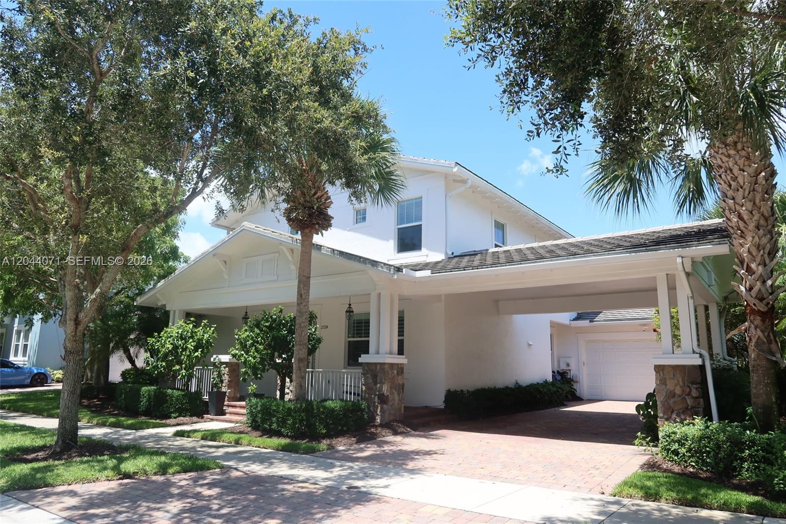A two-story white house features a front porch, a stone-pillared carport, and a brick driveway — 2724 Wymberly Dr, Jupiter FL 33458, JUPITER, FL