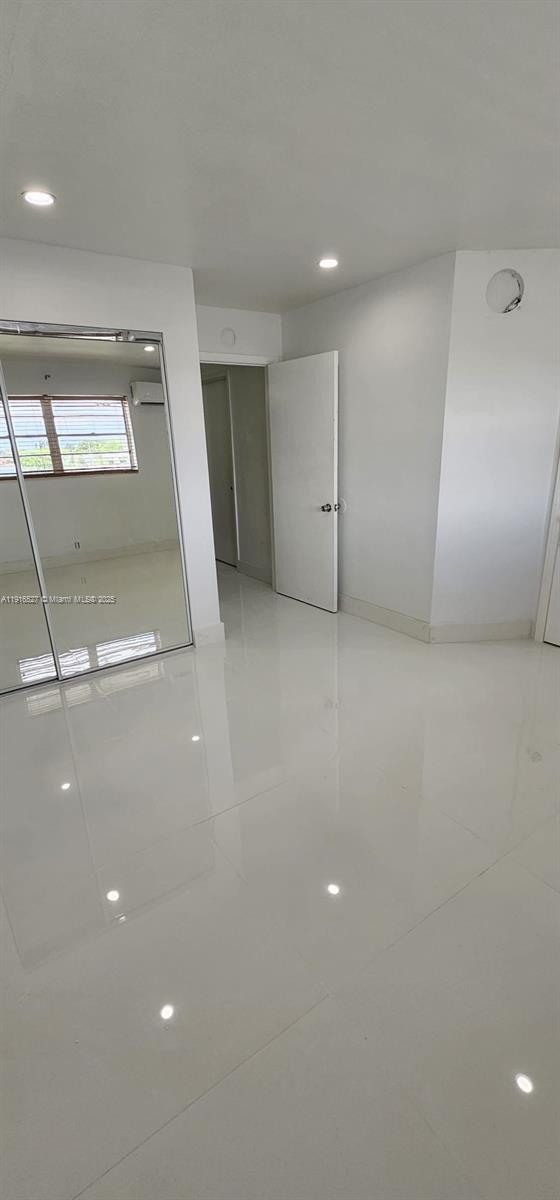 A room with white walls, glossy tile flooring, a mirrored closet, and a closed door — 9375 SW 40th Ter # 203, Miami FL 33165, MIAMI, FL