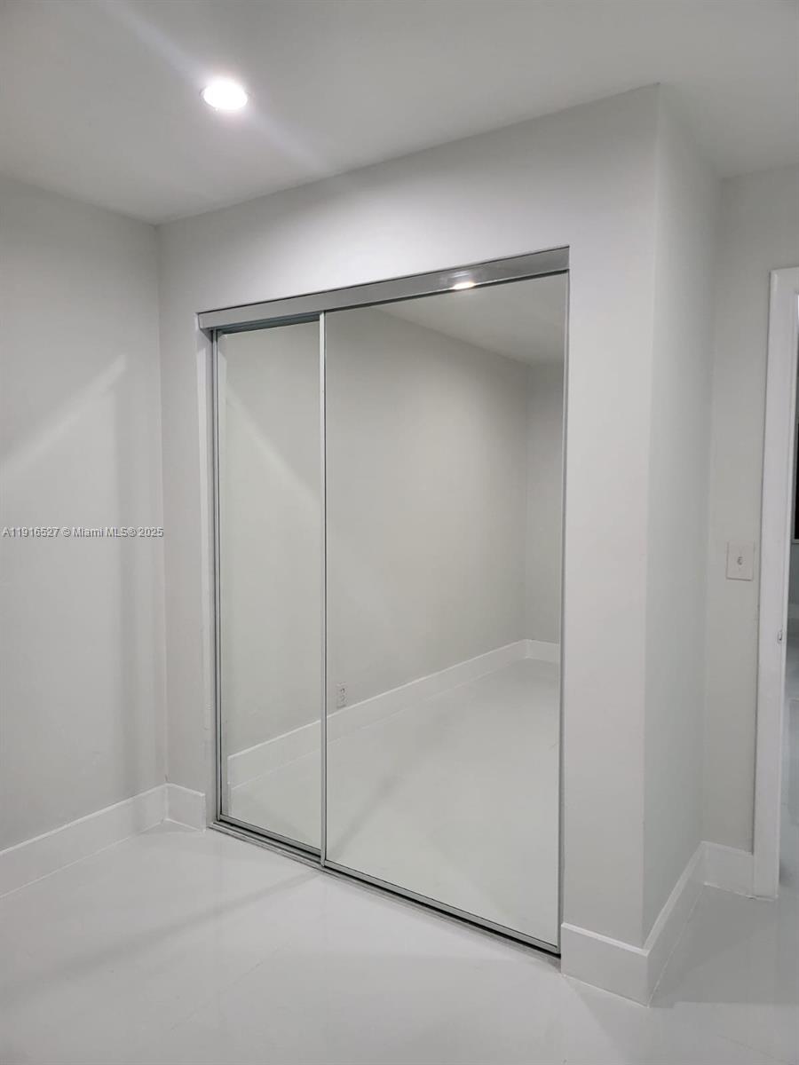 A room features a sliding mirrored closet door with a white floor and walls — 9375 SW 40th Ter # 203, Miami FL 33165, MIAMI, FL