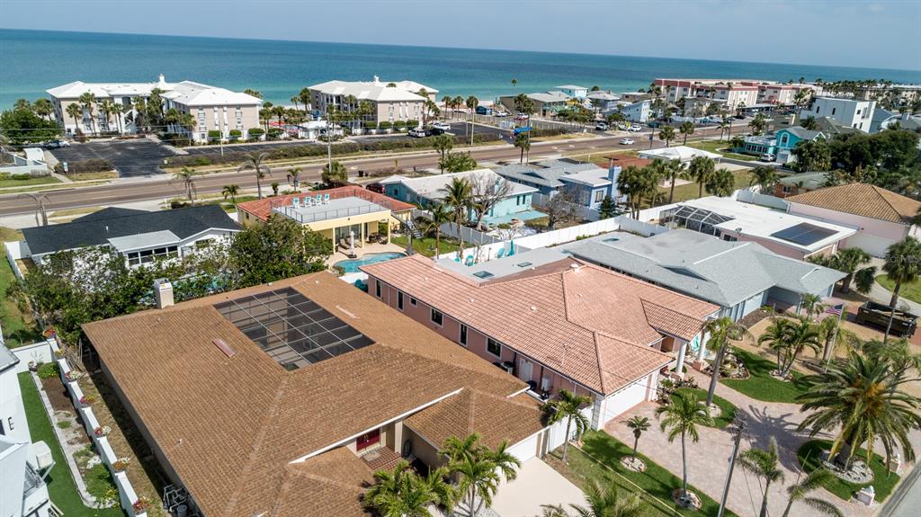 An aerial view shows residential homes with pools and palm trees near a coastal beach — 2504 HIBISCUS DRIVE W, BELLEAIR BEACH, FL