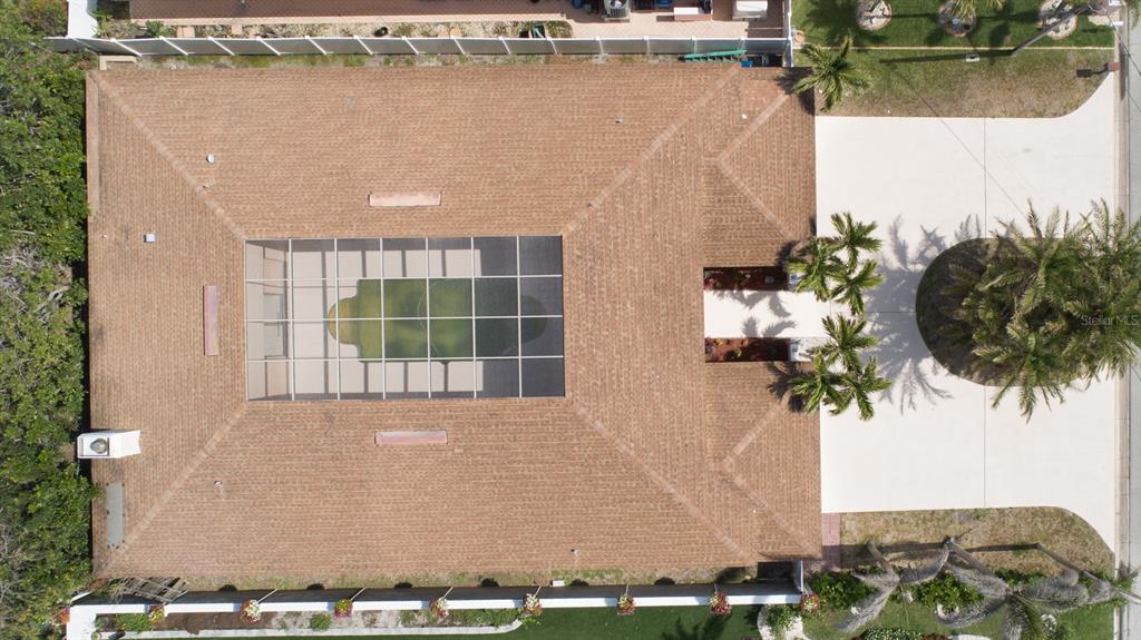 An aerial view of a house with a brown shingled roof and a screened-in pool — 2504 HIBISCUS DRIVE W, BELLEAIR BEACH, FL