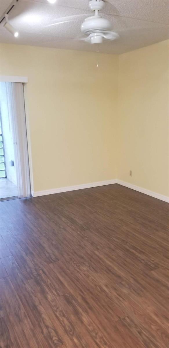An empty room with light yellow walls, wood-look flooring, a ceiling fan, and sliding doors — 2000 Springdale Boulevard # 203, Palm Springs FL 33461, PALM SPRINGS, FL