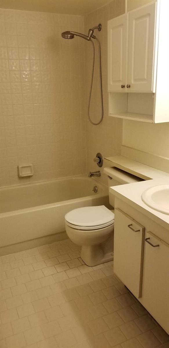 A bathroom features a white vanity, a toilet, and a shower-tub combination with tiled walls — 2000 Springdale Boulevard # 203, Palm Springs FL 33461, PALM SPRINGS, FL