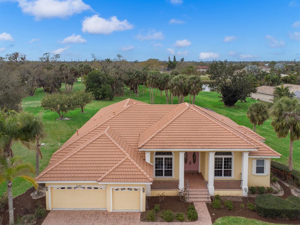 An aerial view of a single-story house with a tan tile roof and two-car garage — 6197 9TH AVENUE CIRCLE NE, BRADENTON, FL