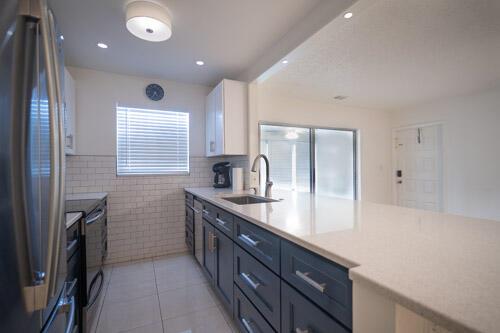 A modern kitchen features dark blue cabinets, white countertops, and a white subway tile backsplash — 235 NW 46th Avenue # B, Delray Beach FL 33445, DELRAY BEACH, FL