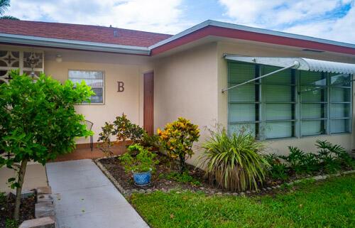 The exterior of a single-story home features a concrete walkway, landscaping, and a letter B — 235 NW 46th Avenue # B, Delray Beach FL 33445, DELRAY BEACH, FL
