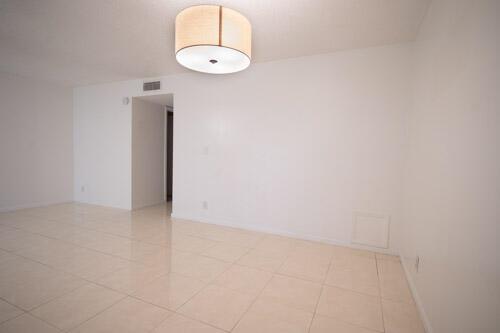 An empty room with white walls, light tile flooring, and a drum-style ceiling light fixture — 235 NW 46th Avenue # B, Delray Beach FL 33445, DELRAY BEACH, FL