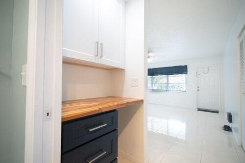 A built-in desk with dark drawers and a wood countertop sits in a white hallway — 235 NW 46th Avenue # B, Delray Beach FL 33445, DELRAY BEACH, FL