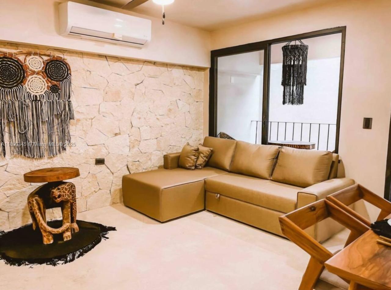 A living room features a tan sectional sofa, a stone accent wall, and decor — Kantuun Tulum Palenque, C. 3 Pte. con # A4, TX 77760, TX