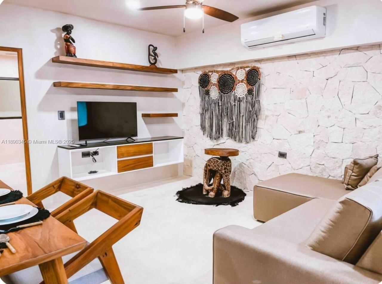A living room features a stone accent wall, floating shelves, a television console, and furniture — Kantuun Tulum Palenque, C. 3 Pte. con # A4, TX 77760, TX