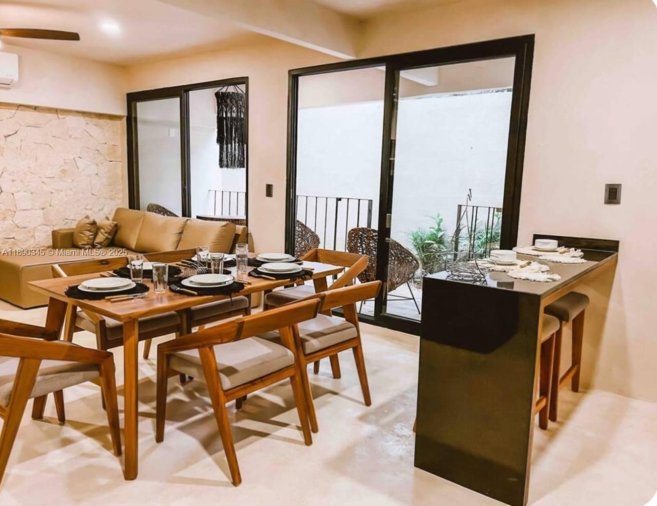 A dining room with a wooden table and chairs next to a black kitchen island — Kantuun Tulum Palenque, C. 3 Pte. con # A4, TX 77760, TX