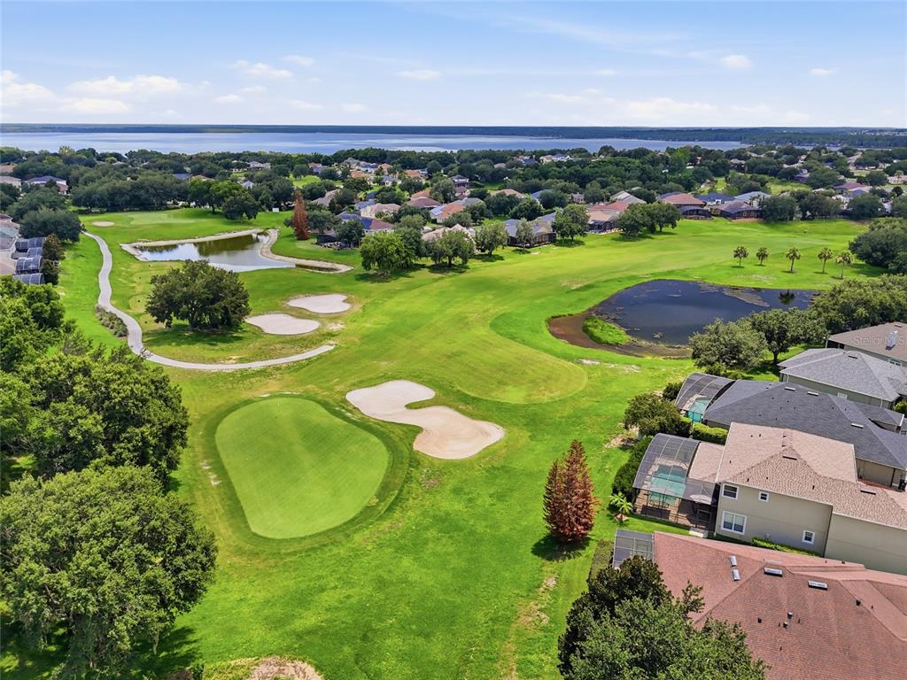 An aerial view of a golf course green with sand traps, ponds, and surrounding houses — 3910 LIBERTY HILL DRIVE, CLERMONT, FL