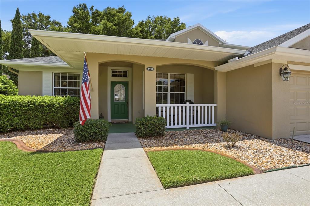 A single-story house exterior features a covered entryway, a green front door, and landscaping — 3910 LIBERTY HILL DRIVE, CLERMONT, FL