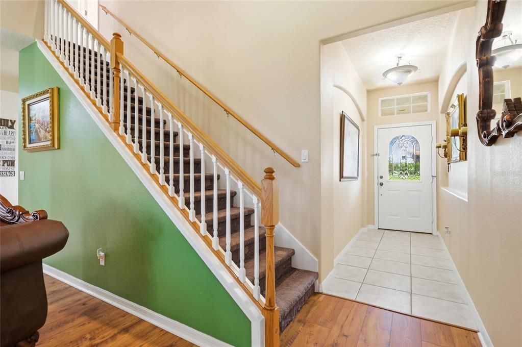 An entryway features a carpeted staircase with a wooden railing, green wall, and tiled floor — 3910 LIBERTY HILL DRIVE, CLERMONT, FL